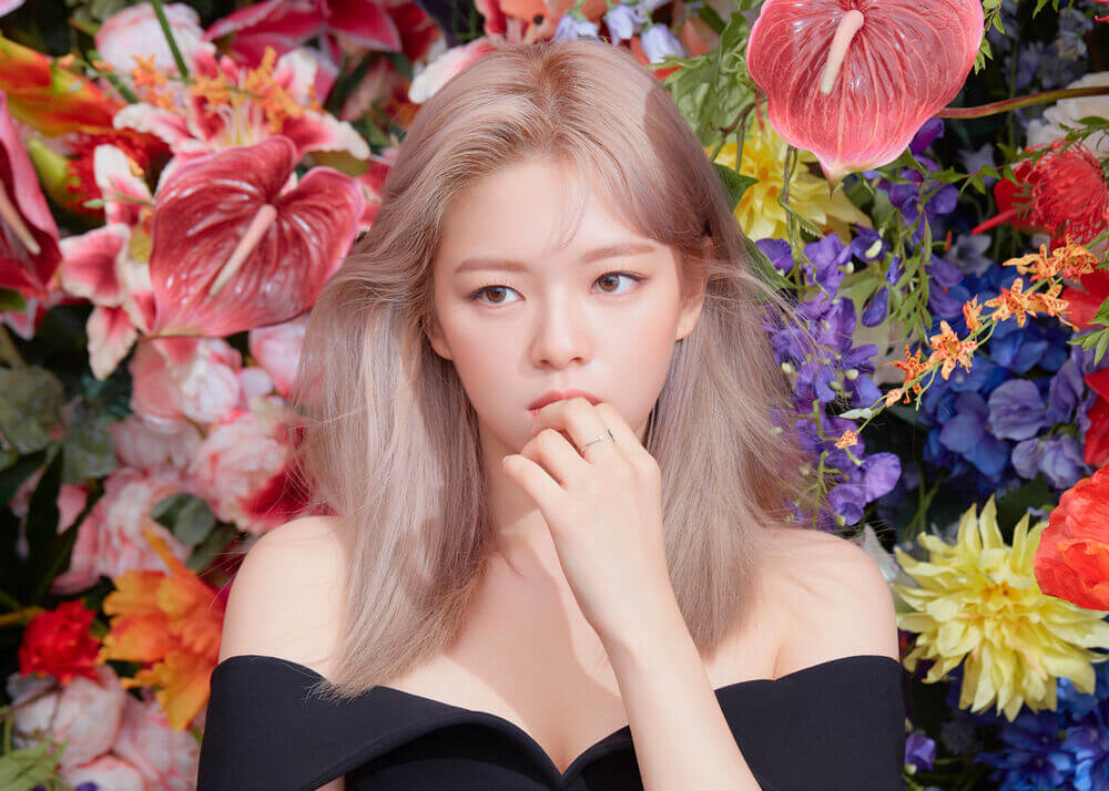 Jeongyeon de frente en el set de more & more con un fondo de flores