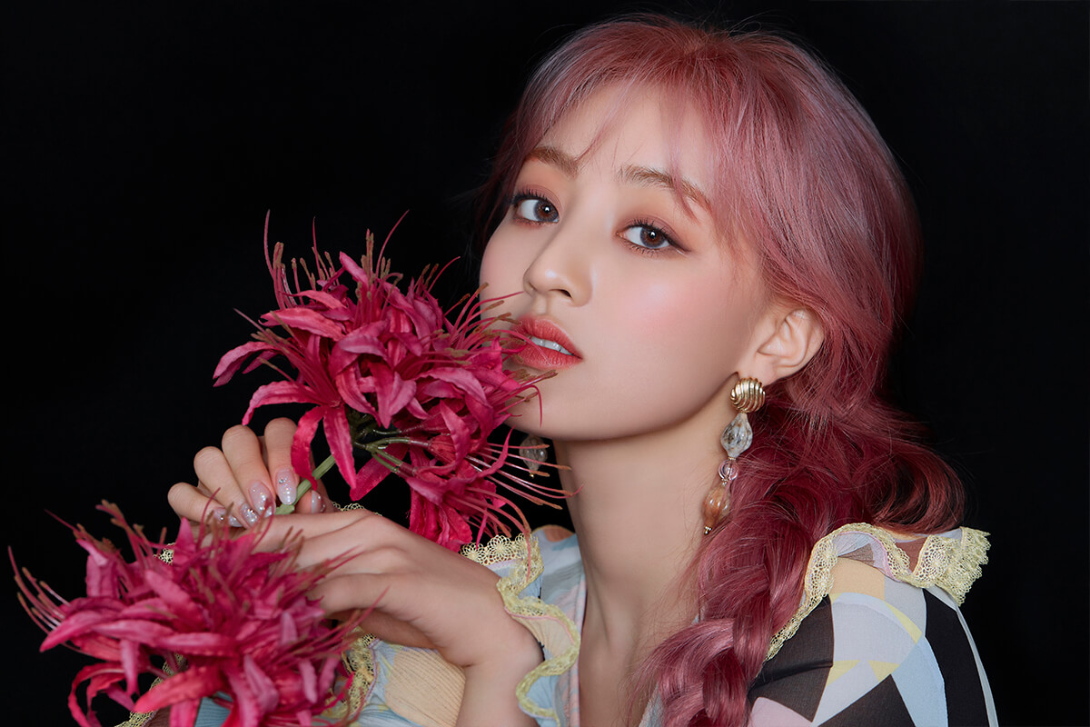 Jihyo de perfil con flores en las mano y un fondo negro para la promoción de more & more